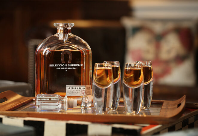 A bottle of Herradura Selección Suprema tequila displayed elegantly on a table.