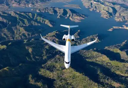 Large long-range private jet flying over beautiful mountains and rivers scenery