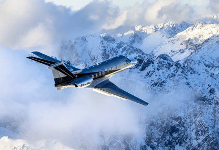 A high end small private jet flying over snowy mountains and cold weather conditions