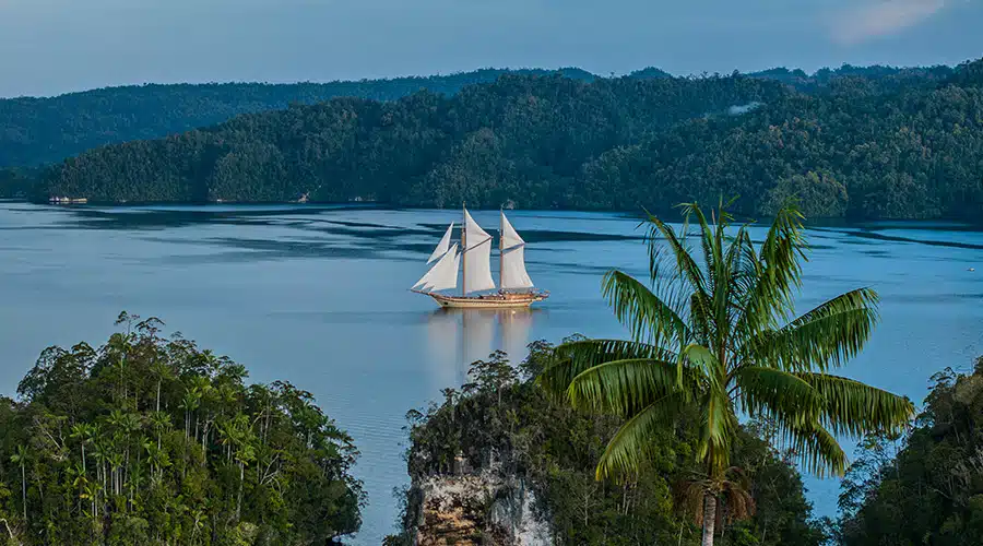 traditional sailing ship A traditional sailing ship with white sails glides through a serene body of water