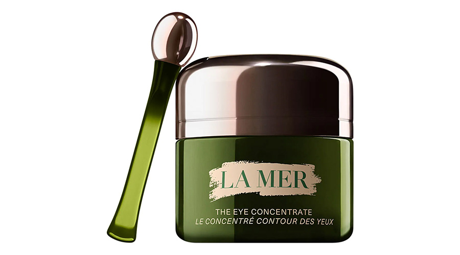 A green jar of La Mer The Eye Concentrate with a matching metallic green applicator wand, both set against a white background. The jar features gold labeling and a silver lid.