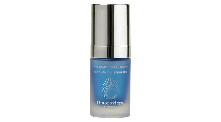A blue bottle of Omorovicza Blue Diamond Eye Cream with a silver cap, featuring white text and a sunburst logo on the front.
