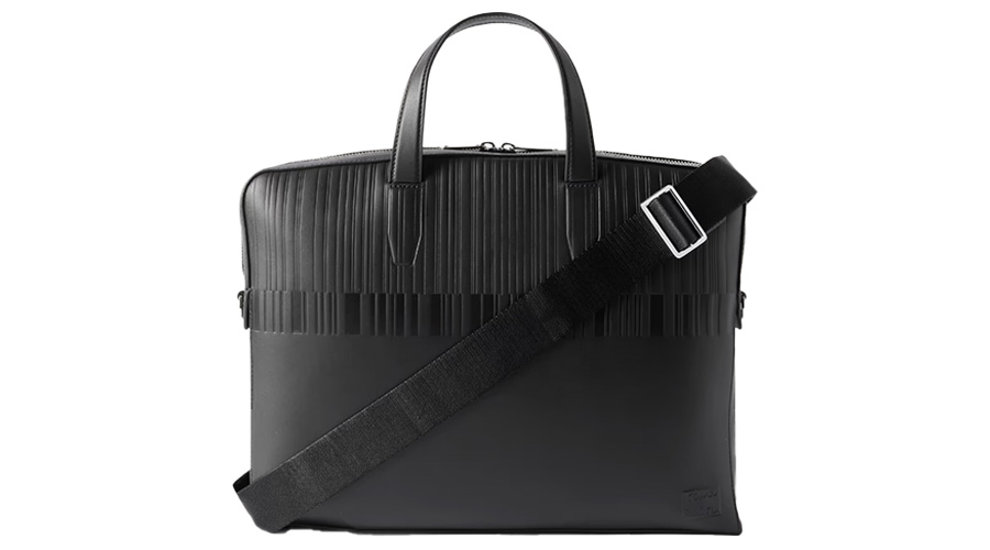 A black briefcase with dual top handles, a textured upper section, a smooth lower section, and an adjustable shoulder strap with a metal buckle.