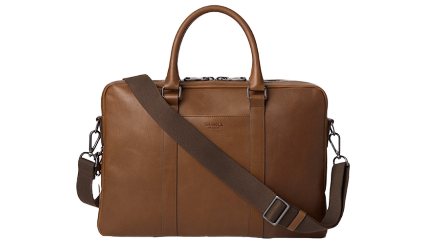 A brown leather briefcase with two handles and a detachable, adjustable shoulder strap. The bag has a minimalist design with subtle stitching and a smooth finish.