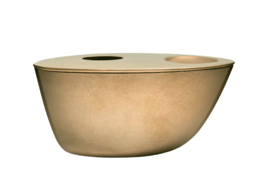 A gold-colored, oval-shaped container with a smooth, matte finish. Its flat lid has two circular openings of different sizes on one side.