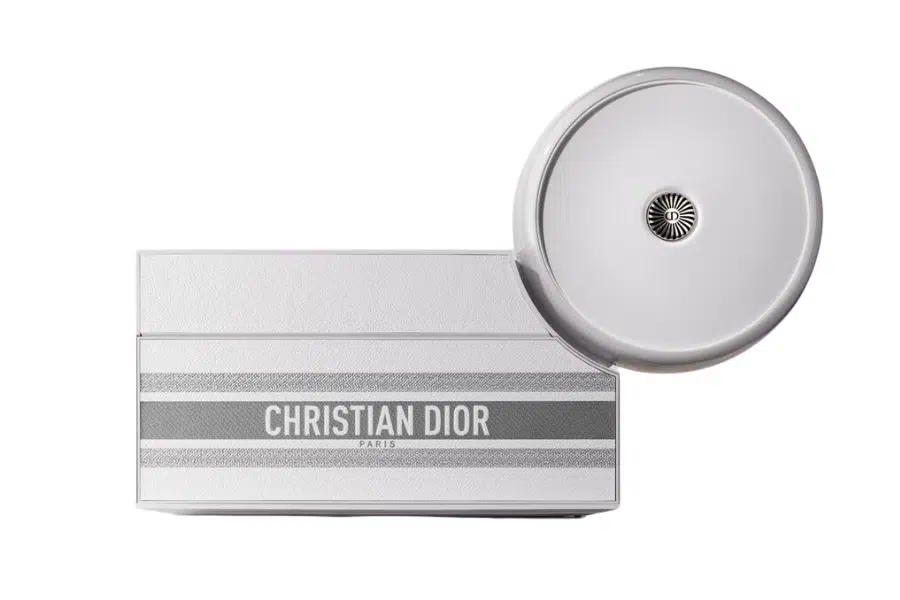 A rectangular silver Christian Dior box with a circular lid partially open, displaying the brand name and “Paris” printed in bold letters across the front.