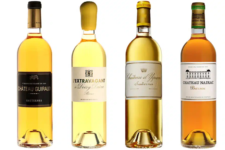 Four bottles of French dessert wine are shown side by side, each with distinct labels: Château Guiraud, L’Extravagant de Doisy Daëne, Château d’Yquem Sauternes, and Château Nairac Barsac.