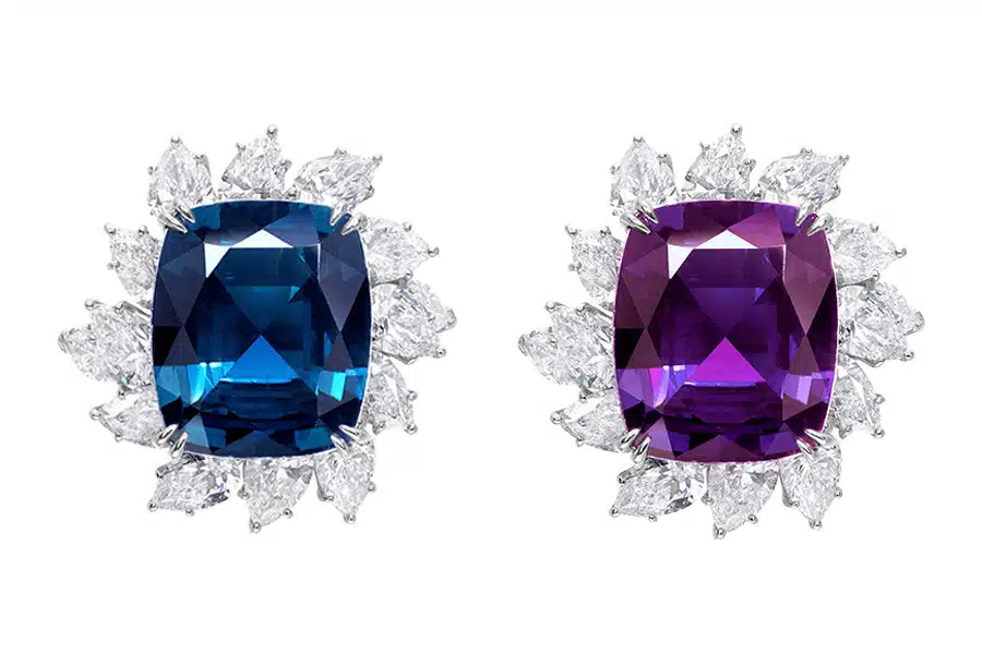 A pair of gemstone earrings: one features a large blue stone and the other a large purple stone, both surrounded by a halo of clear, marquise-cut gemstones.