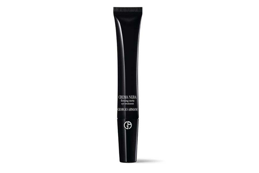 A sleek black tube of Giorgio Armani Crema Nera Firming Eye Serum stands upright against a white background, featuring silver text and the brand’s logo near the base.