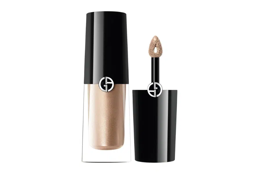 A gold liquid eyeshadow in a clear tube with a glossy black cap, shown next to an open applicator wand with a sponge tip, both featuring a white Armani logo.