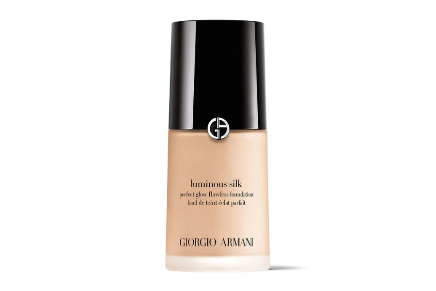 A bottle of Giorgio Armani Luminous Silk foundation with a black cap and clear glass showing beige liquid, featuring the brand logo and product name on the front.