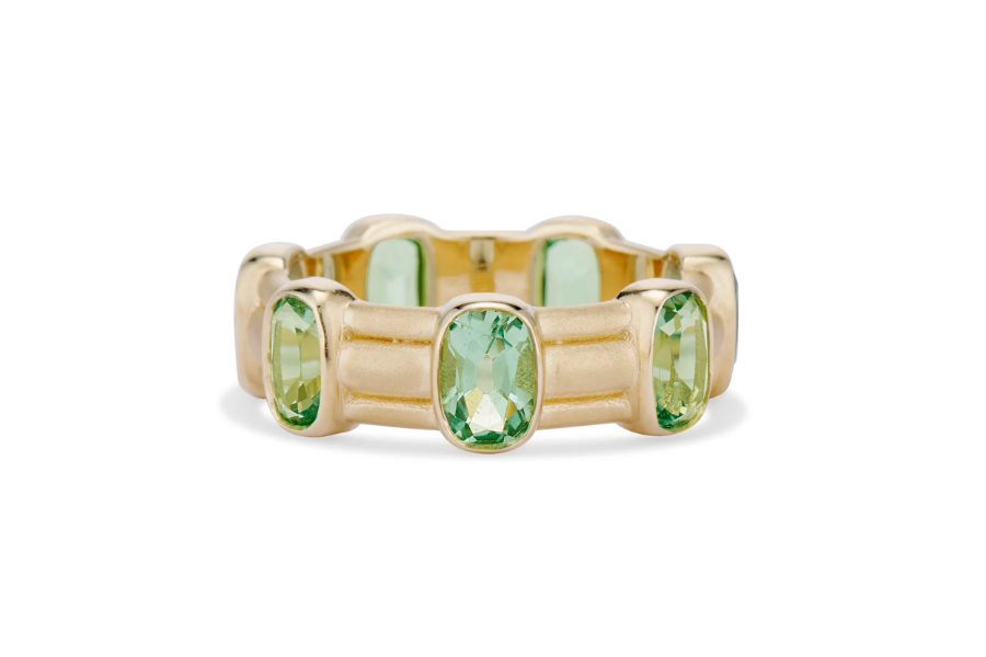 A gold ring featuring multiple rectangular green gemstones set evenly around the band.