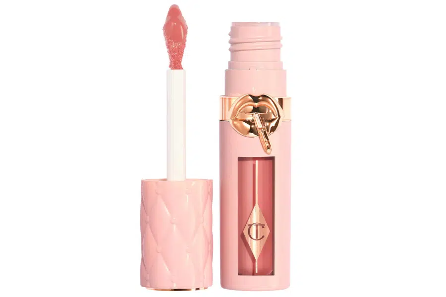 A pink, quilted-pattern lip gloss tube with a gold logo, shown open with a wand applicator covered in nude-pink gloss.