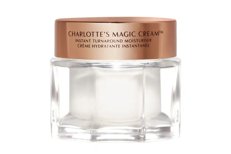 A clear glass jar with a shiny rose gold lid labeled Charlotte’s Magic Cream Instant Turnaround Moisturiser. The jar is empty and displayed against a plain white background.