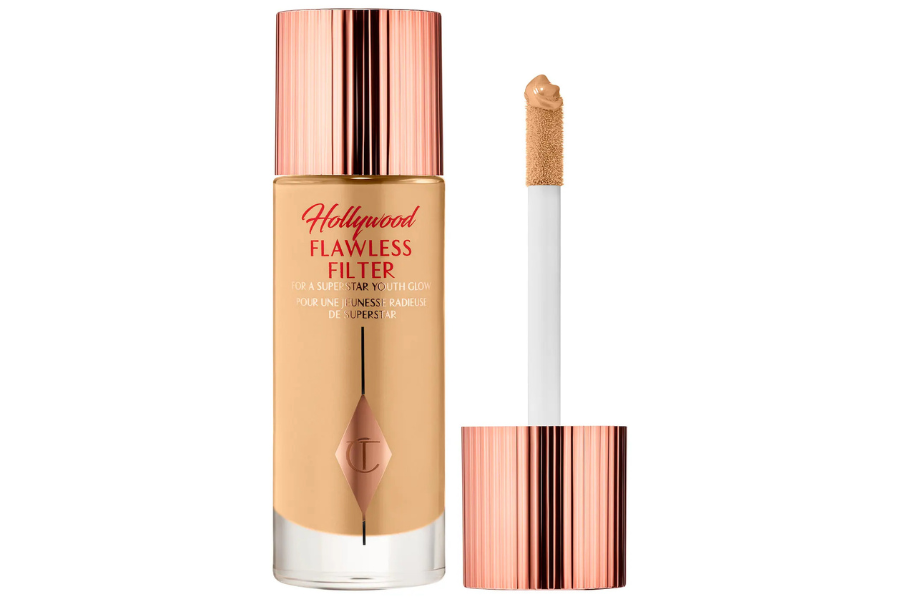 A bottle of Charlotte Tilbury Hollywood Flawless Filter foundation with a rose gold cap, shown beside its applicator wand with product on the tip.