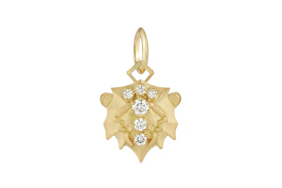 A gold pendant shaped like a stylized lion’s face, featuring four round, sparkling diamonds set vertically in the center, with a loop at the top for attaching to a chain.