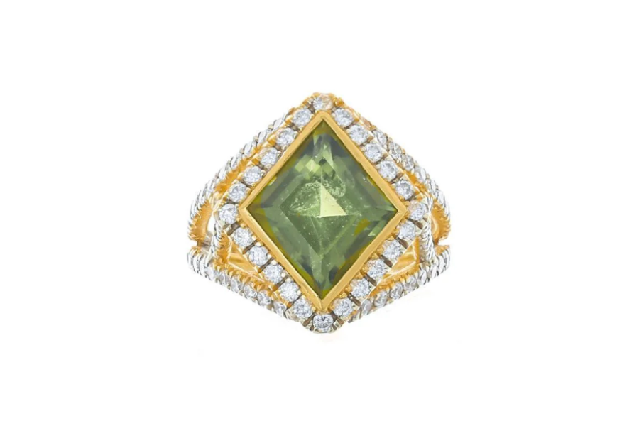 A gold ring featuring a large, square-cut green gemstone at the center, surrounded by two rows of sparkling white diamonds on a textured gold and silver band.