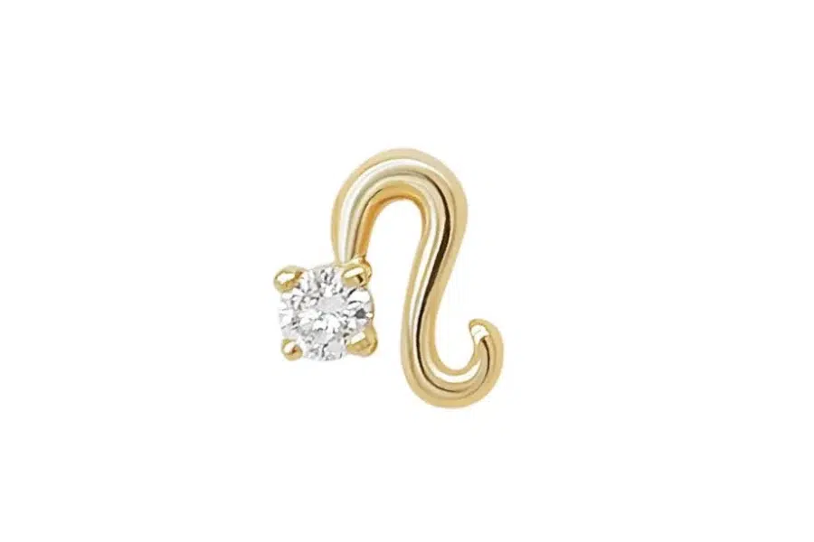 A gold earring shaped like a stylized S or swirl, featuring a single round white gemstone set on one side against a plain white background.