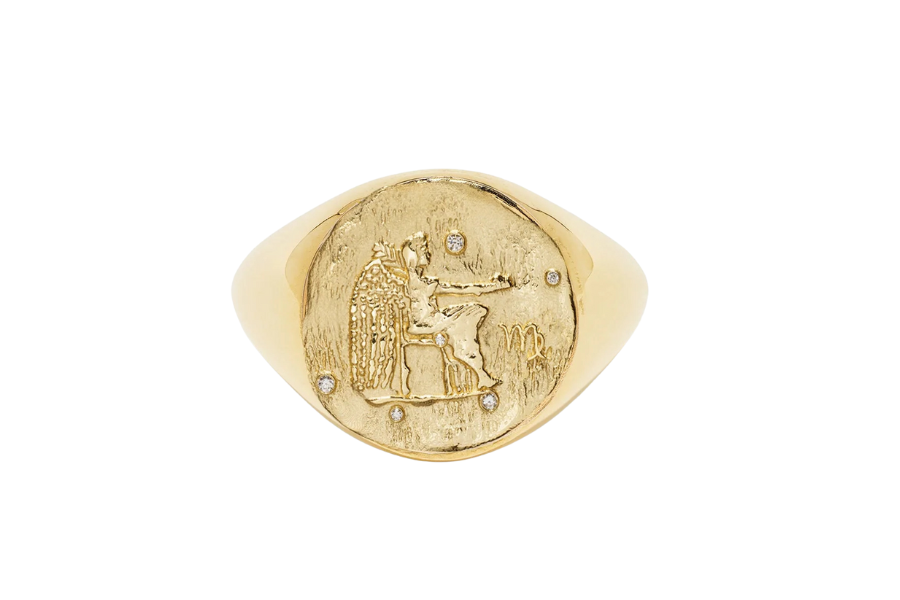 A gold signet ring featuring an engraved figure seated on a throne, with small embedded gemstones accenting the design.