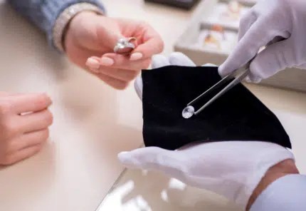 A jeweler handling a diamond in front of a customer
