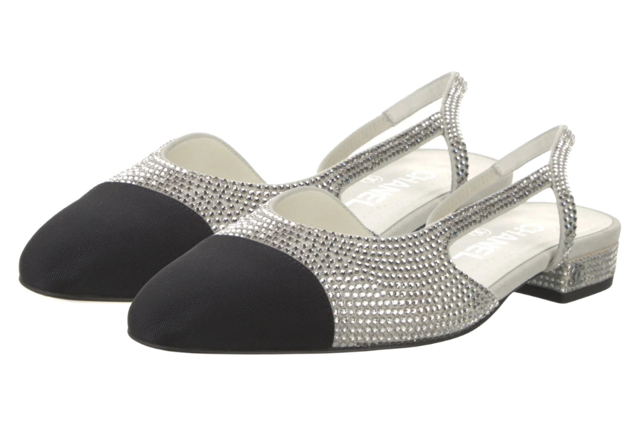 A pair of elegant slingback shoes with black toe caps, silver rhinestone-encrusted uppers, and low block heels.