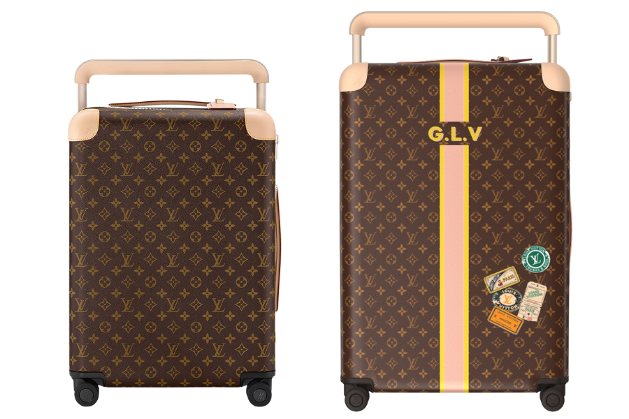 Two luxury rolling suitcases with brown monogram patterns, tan handles, and accents. The front suitcase has the initials G.L.V, a yellow stripe, and travel sticker designs. The back shows the suitcase from behind.
