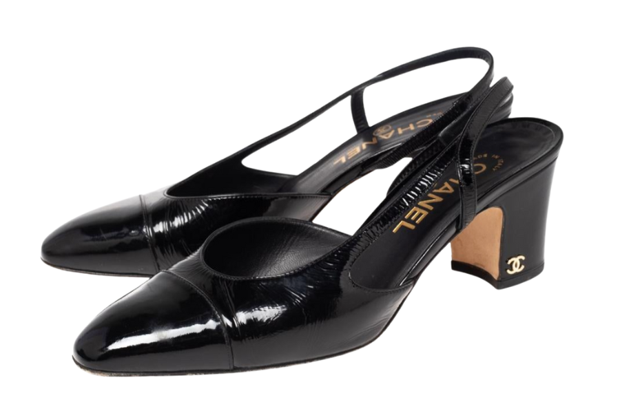 A pair of black patent leather slingback heels with pointed toes and block heels, featuring the Chanel logo in gold on the side of each heel.