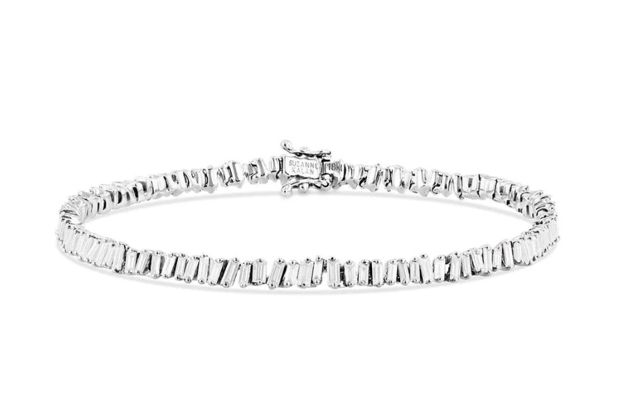 A delicate silver tennis bracelet featuring a continuous row of rectangular, clear gemstones and a simple clasp, displayed on a white background.
