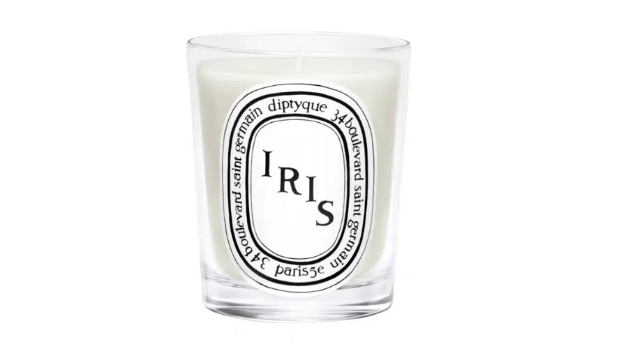 A white Diptyque candle in a clear glass holder with a white and black oval label that reads Iris and includes 34 Boulevard Saint Germain Paris around the border.