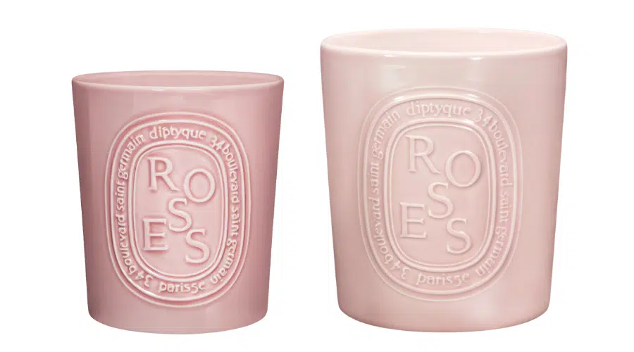 Two pink ceramic containers with embossed oval labels reading ROSES and diptyque 34 boulevard saint germain paris. One container is smaller and the other is larger, both in a soft pastel shade.