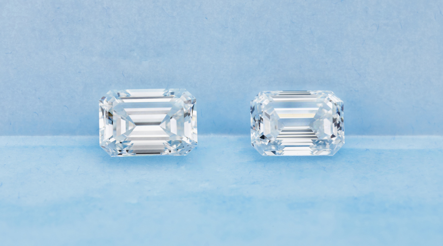 Two rectangular, emerald-cut diamonds are placed side by side on a light blue surface with a matching blue background.