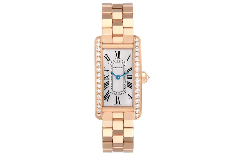 A rose gold wristwatch with a rectangular face, black Roman numerals, blue hands, a white dial, and diamond accents along the bezel, on a matching rose gold link bracelet.