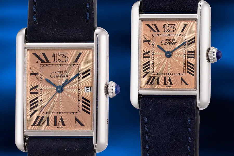 Two Cartier wristwatches with rectangular rose gold faces, black Roman numerals, blue hands, a date window, and dark leather straps are displayed against a blue background.