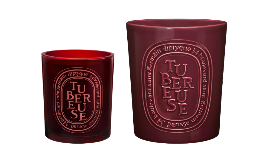Two red Diptyque candles of different sizes with the word Tubereuse and French writing on oval labels on the front of each glass holder.