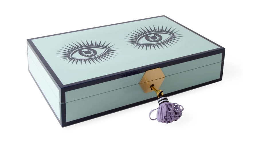 A light blue rectangular box with black edges, decorated with two large illustrated eyes on the lid. It has a gold hexagonal clasp with a purple tassel attached.