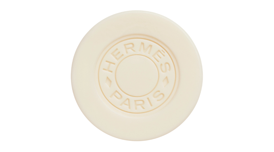 A round, cream-colored soap bar embossed with the words HERMÈS PARIS in a circular design in the center, set against a white background.