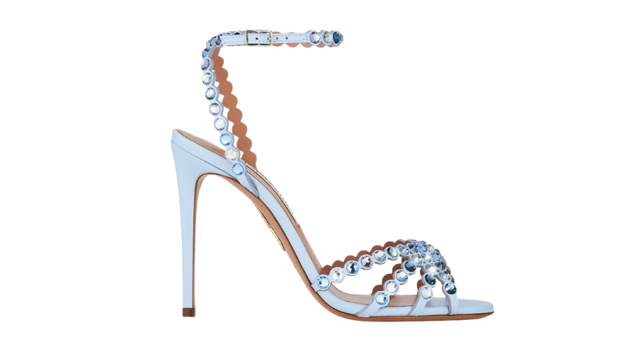 A light blue high-heeled sandal with a thin ankle strap and multiple straps across the foot, all adorned with shiny, round gemstones.