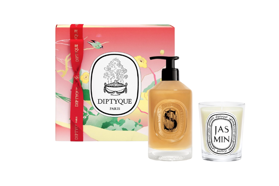 A Diptyque Paris gift set including a colorful, illustrated box, a pump bottle of scented liquid soap, and a white candle labeled “Jasmin.”.