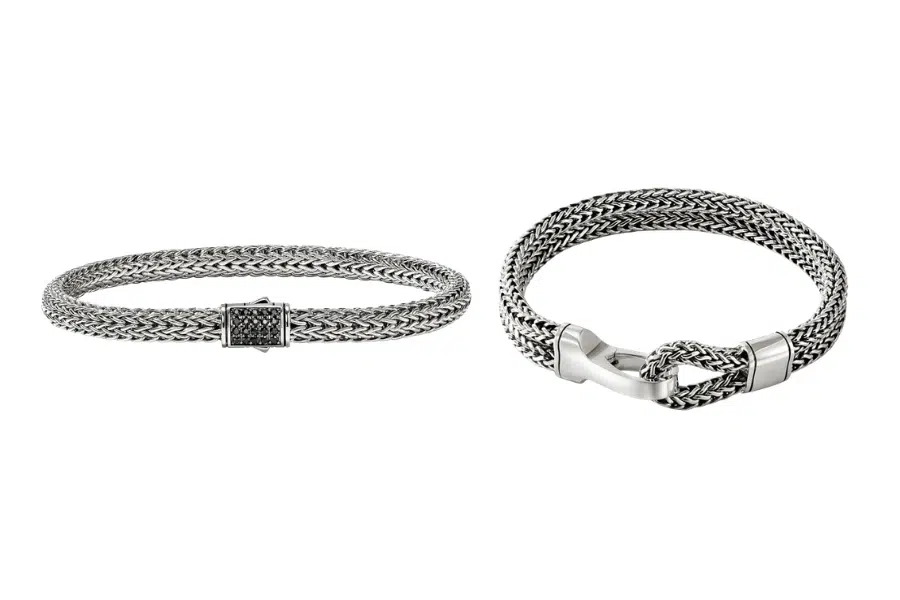 Two silver woven chain bracelets on a white background; the left bracelet has a rectangular clasp, while the right bracelet features an intricate knot design with smooth metal detailing.