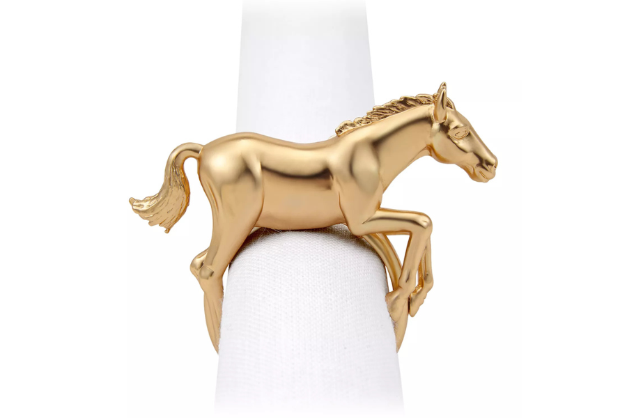 A gold napkin ring shaped like a galloping horse is wrapped around a white napkin, displayed against a plain white background.