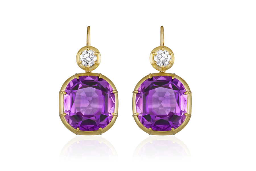 A pair of gold drop earrings featuring large, faceted purple gemstones and small round white gemstones above them, set against a white background.