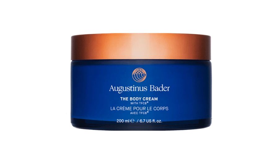 A blue jar of Augustinus Bader The Body Cream with a copper-colored lid, labeled in white text and containing 200 ml (6.7 fl oz) of product.