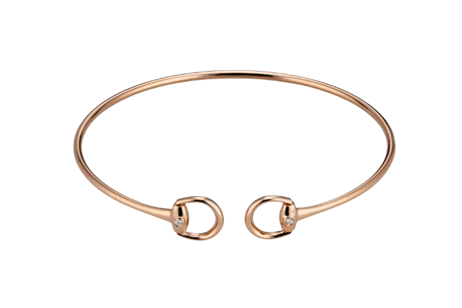A thin, open-ended rose gold bracelet with rounded ends, each featuring a small circular design set with a single clear gemstone.