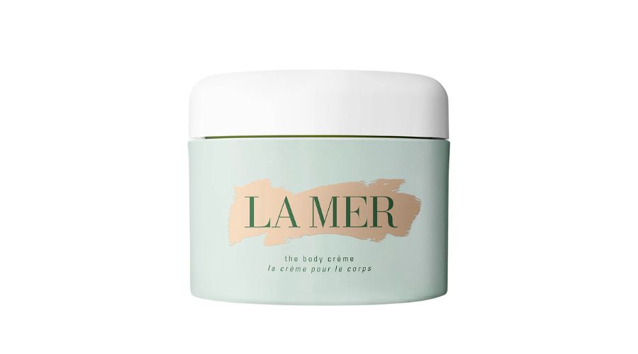 A jar of La Mer The Body Crème, with a light green container, a white lid, and LA MER written in large letters on the front.