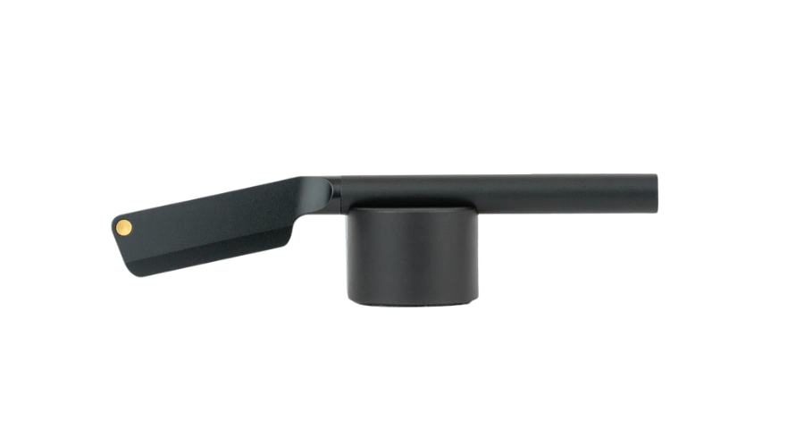 A matte black metal spice grinder with a cylindrical base and a long horizontal handle, viewed from the side against a white background.