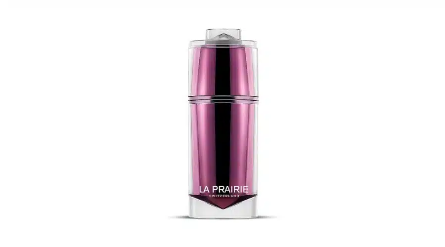 A sleek, tall, pink and silver cosmetic bottle labeled La Prairie Switzerland stands upright against a plain white background.