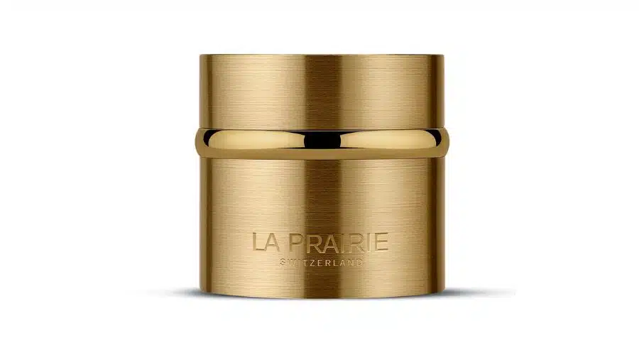 A gold cylindrical jar with a shiny finish and LA PRAIRIE SWITZERLAND engraved on the front, set against a plain white background.