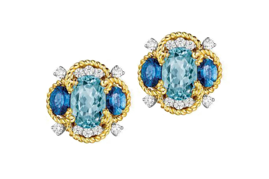 Gold earrings featuring large oval aquamarine gemstones in the center, surrounded by blue sapphires, diamonds, and twisted gold detailing, displayed on a white background.