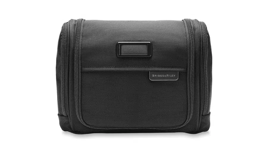 A black Briggs & Riley toiletry bag with a rectangular shape, a front zippered pocket, a small logo label, and a textured fabric exterior.