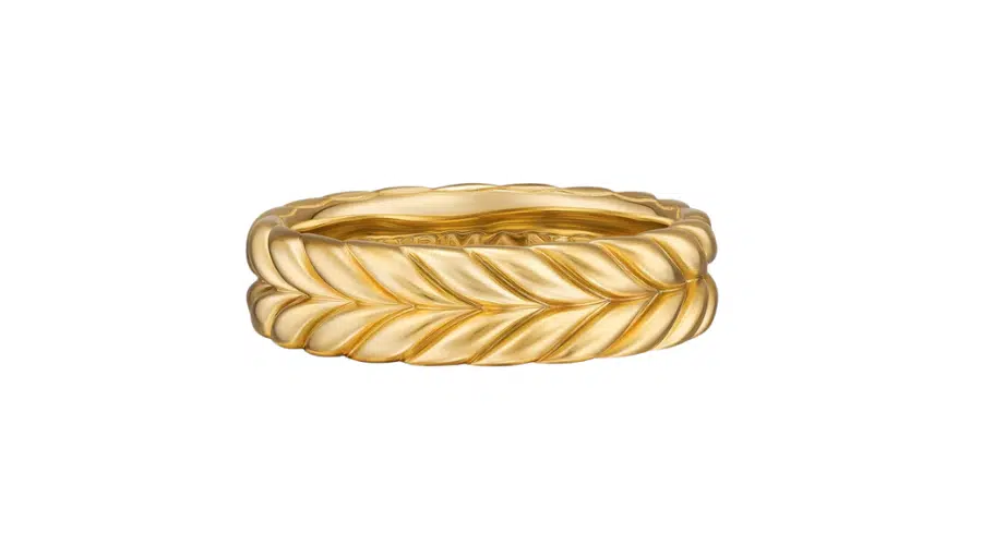 A gold ring with a twisted, rope-like design, featuring a textured, leaf or braid pattern encircling the band. The background is plain white.